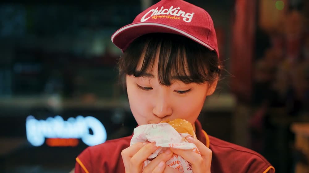 A Chicking crew member eating a chicken burger